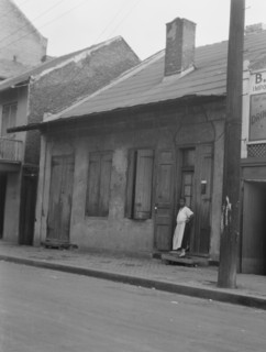 View from across street of a woman standing by a doorway in the French Quarter, New..., c1920-c1926. Creator: Arnold Genthe.