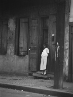 View from across street of a woman standing in a doorway in the French Quarter, New..., c1920-c1926. Creator: Arnold Genthe.