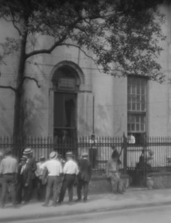 Men standing or sitting in front of the former Bank of Louisiana, 334 Royal Street..., c1920-1926. Creator: Arnold Genthe.