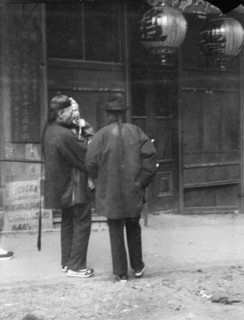 Two men, one holding a child, standing in the street, Chinatown, San Francisco, c1896-1906. Creator: Arnold Genthe.