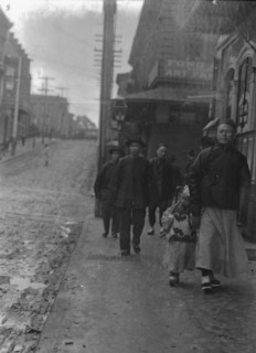 Man and a boy walking down a sidewalk with other people, Chinatown, San Francisco, c1896-1906. Creator: Arnold Genthe.