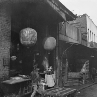 Two women and a child walking down a sidewalk betwen crates, Chinatown, San Francisco, c1896-1906. Creator: Arnold Genthe.