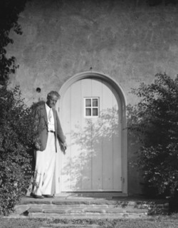 Arnold Genthe standing outside by a door, between 1911 and 1942. Creator: Arnold Genthe.