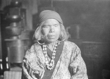 Ainu woman wearing a headscarf, earrings, and a necklace, 1908. Creator: Arnold Genthe.