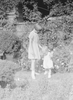 Children of Mrs. George Eustis standing outdoors in a garden, between 1911 and 1942. Creator: Arnold Genthe.