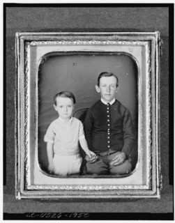 Unidentified boy seated in chair with child standing to left, three-quarter..., between 1850 & 1860. Creator: Unknown.