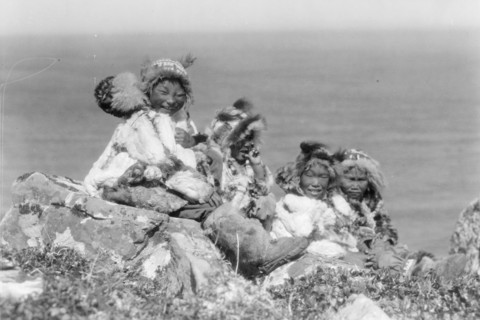 Four Eskimo children, at edge of cliff, in holiday costume, Nunivak, Alaska, c1929. Creator: Edward Sheriff Curtis.