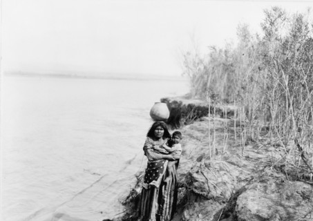 Mohave woman carrying water on her head and holding child, c1903. Creator: Edward Sheriff Curtis.