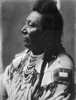 Plenty Coups, Crow Indian, head-and-shoulders portrait, facing left, pompadour, temple..., c1908. Creator: Edward Sheriff Curtis.