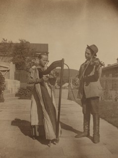 Street musicians with a harp and violin in the upper yard of Dom Smith, Vladivostok, Russia, (1899?) Creator: Eleanor Lord Pray.