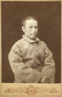 Half-length portrait of a man in convict coat, seated, facing right, between 1880 and 1886. Creator: Unknown.