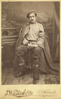 Full-length portrait of a man in convict clothing and leg irons, seated..., between 1880 and 1886. Creator: Unknown.