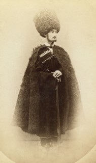Full-length portrait of a man in cape and sheep skin hat, holding a rifle..., between 1870 and 86. Creator: Unknown.