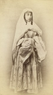 Full-length portrait of a woman, facing slightly right, in traditional dress, between 1870 and 1886. Creator: Unknown.