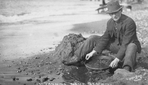 Man panning gold on Nome Beach, between c1900 and c1930. Creator: Lomen Brothers.