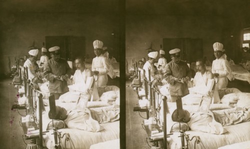 Nurses and a doctor attending wounded soldiers on a hospital ward, c1905. Creator: Underwood & Underwood.