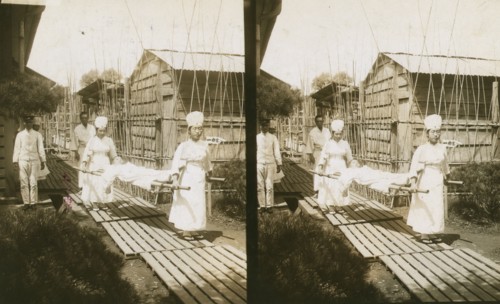 Japanese nurses carrying a patient on a stretcher, c1905. Creator: Underwood & Underwood.