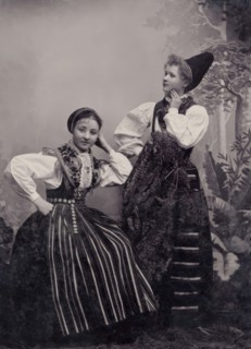 Studio portrait of two young girls posing in folk costumes from Dalarna, 1880-1907. Creator: Helene Edlund.