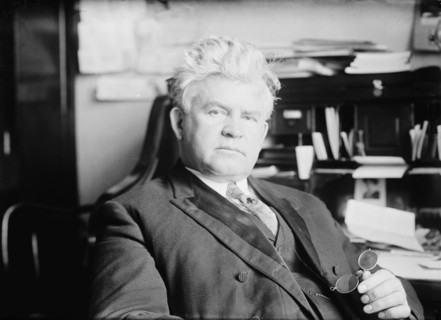 H.T. Rainey, holding bifocals, at desk, 1911. Creator: Bain News Service.
