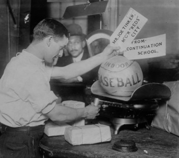 Medicine ball being weighed by Post Office employee; shipping tags read: Mr. Joe Tinker..., 1913. Creator: Bain News Service.
