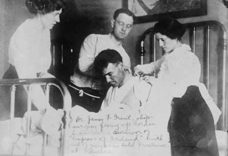 Dr. James F. Grant, ship's surgeon, fixing up Gordon G. Davidson, survivor of EMPRESS OF..., 1914. Creator: Bain News Service.