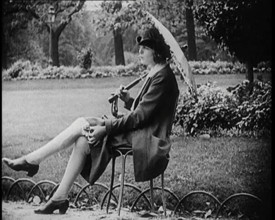 Fashionable Lady Sitting in a Garden Wearing Headphones and Carrying a Parasol, 1922. Creator: British Pathe Ltd.