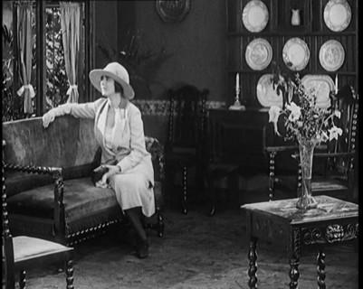 A Female Civilian Modelling a Two Piece Suit and Hat Sitting on a Sofa by a Window in a Draw... 1920 Creator: British Pathe Ltd.