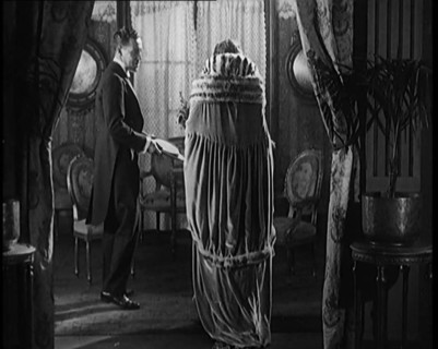 A Civilian Couple Wearing Evening Outfits Entering a Drawing Room, 1920. Creator: British Pathe Ltd.
