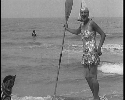 Female Civilian Wearing a Sequinned Swimsuit with a Dog in a Striped Shirt and Beret on a Canoe,1920 Creator: British Pathe Ltd.