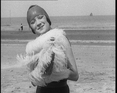 Female Civilian Wearing a Swimsuit Holding a Feathered Parasol at the Beach, 1920. Creator: British Pathe Ltd.
