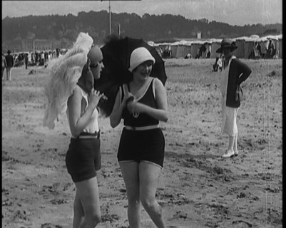 Two Young Female Civilians Wearing Swimsuits Holding Feathered Parasols on a Beach, 1920. Creator: British Pathe Ltd.