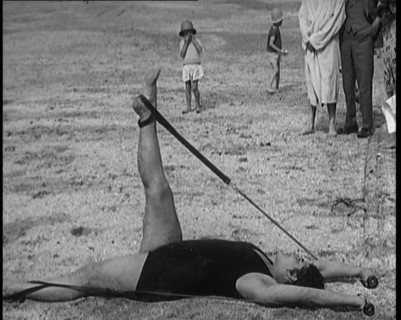 Female Civilian Laying on the Sand Exercising with an Elastic Band on a Beach, 1920. Creator: British Pathe Ltd.
