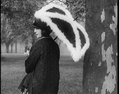 Female Civilian Dressed Glamorously Holding a Fur Trimmed Parasol in a Park, 1920. Creator: British Pathe Ltd.