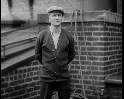 Male Civilian Wearing a Cardigan and a Flatcap Standing in Front of a Wall Talking at the..., 1930. Creator: British Pathe Ltd.