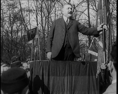 A Male Civilian Makes a Speech from a Stand in Front of a Crowd of Male Civilians Carrying..., 1924. Creator: British Pathe Ltd.