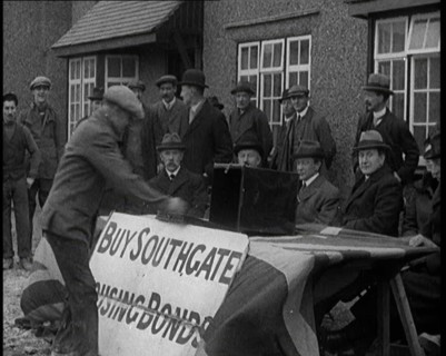 Men Buying Housing Bonds in Southgate. They Take a Piece of Paper from a Box on the Table..., 1921. Creator: British Pathe Ltd.