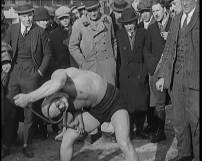 A Strongman Bending an Iron Bar Around His Head, 1921. Creator: British Pathe Ltd.
