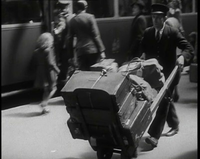 A Male Train Station Porter Pushing a Sack Barrow With Suitcases and Bags on it Along..., 1938. Creator: British Pathe Ltd.