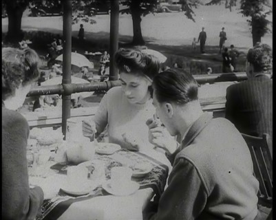 A Close up of Two Women and a Man Having Food and Drink on the Roof Terrace at  the Tea..., 1939. Creator: British Pathe Ltd.