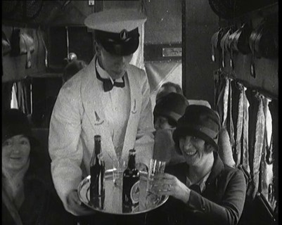 A Male Waiter Serves Smiling and Laughing Passengers Drinks  Inside an Aircraft, 1920s. Creator: British Pathe Ltd.