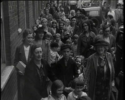British Women and Child Evacuees Walking Along the Pavement of a Residential Street Next..., 1939. Creator: British Pathe Ltd.
