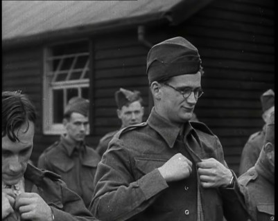 Close up on a Male British Soldier Wearing a Side Cap and Round-Rimmed Glasses Buttoning up..., 1939 Creator: British Pathe Ltd.