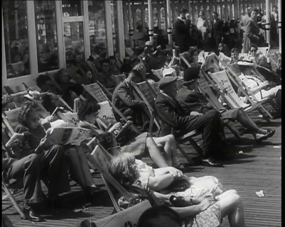 Lines of Men and Women Sitting in Deckchairs on a Pier at  Brighton With Several Reading..., 1939. Creator: British Pathe Ltd.
