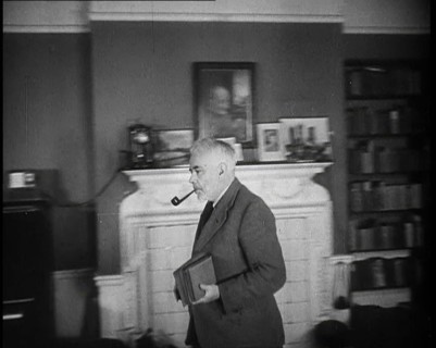 C.E.M Joad Taking Some Books to His Desk, 1930s. Creator: British Pathe Ltd.