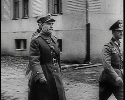 A Male Polish Army Commander Walking Past the Corner of a Large Building With Two Male... 1939. Creator: British Pathe Ltd.