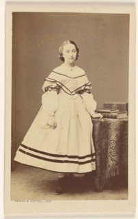 Unidentified woman standing near a table with books on top, 1865-1875. Creator: Bayard & Bertall.