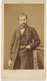 Unidentified well-dressed bearded man standing, elbow on books on a table, 1865-1870. Creator: Bayard & Bertall.