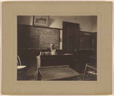 Portrait of a male mathematics teacher with moustache seated at his classroom desk, about 1900. Creator: Unknown.