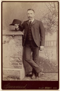 Studio portrait of a man holding a hat, about 1885. Creator: WH Greenwood.