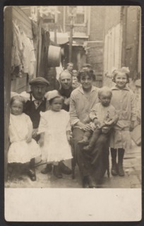 Family portrait in tenement alley, about 1913-1925. Creator: John Frank Keith.